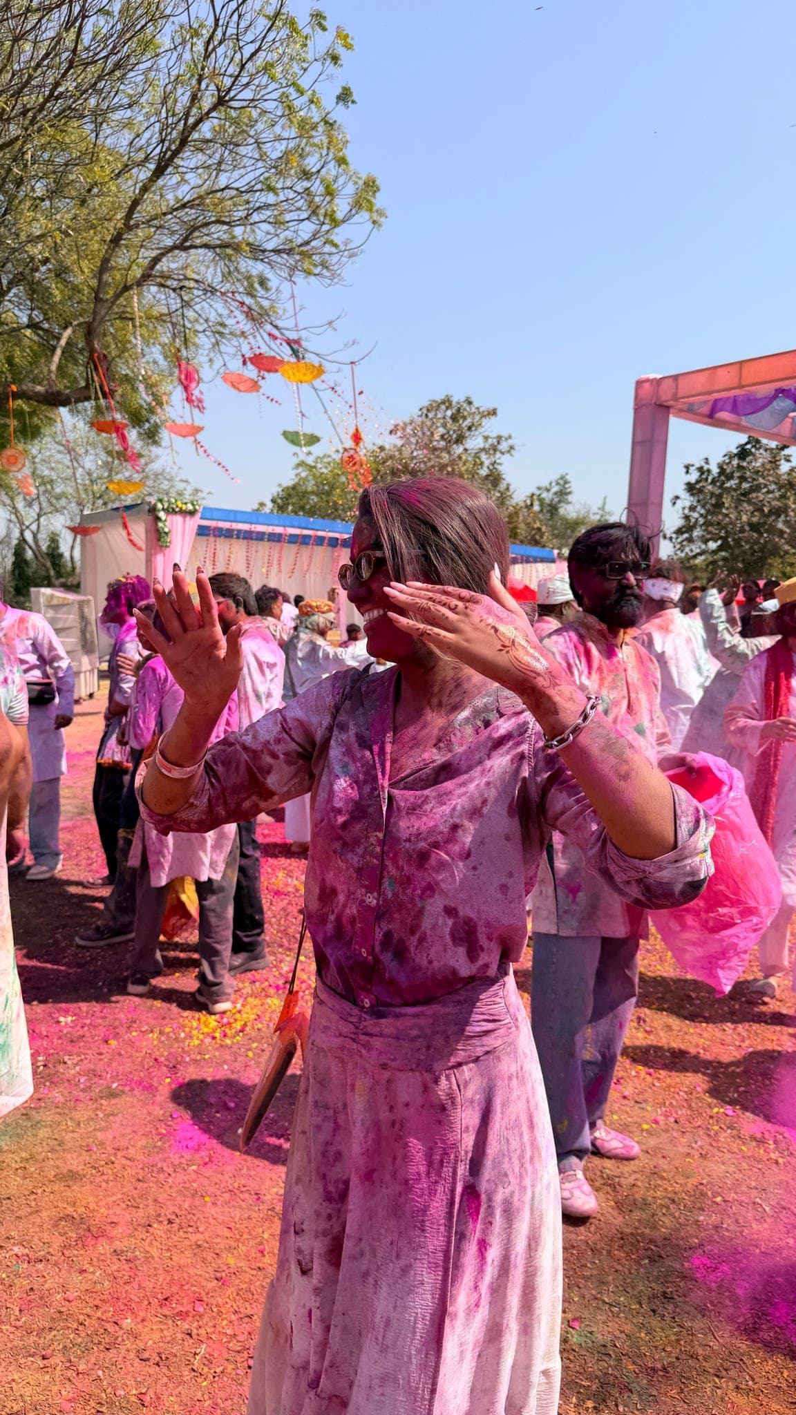 A traveller dancing through clouds of pink powder at the village Holi party